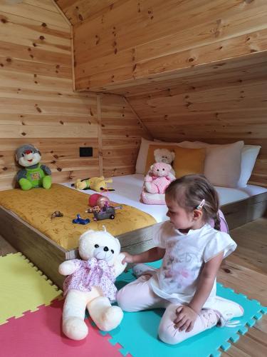 a little girl sitting on a bed with stuffed animals at Dream House Hotel & Spa in Kolašin