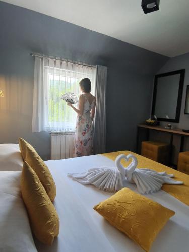 a woman standing in front of a bed with two swans at Dream House Hotel & Spa in Kolašin
