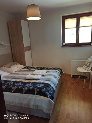 een slaapkamer met een bed, een stoel en een raam bij Apartament Krokus SPA in Kościelisko
