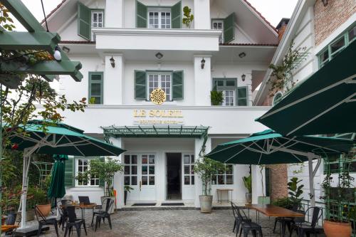 a hotel with tables and chairs in front of a building at Le Soleil Boutique Hotel in Da Lat