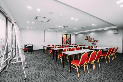 une salle de conférence avec des chaises rouges, des tables et un écran dans l'établissement B Lot Hotel, à Kuala Lumpur