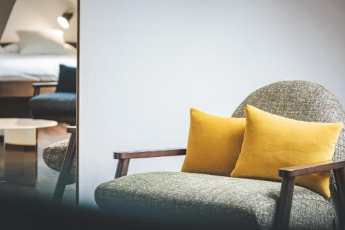 a chair with a yellow pillow in a room at Hotel Bernina Geneva in Geneva