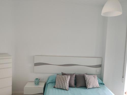 a white bedroom with a bed with pillows at BlancMar Apartament in Calpe