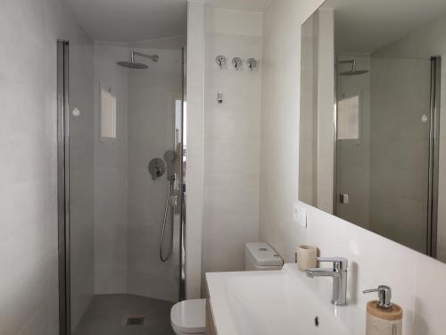 a white bathroom with a shower and a sink at BlancMar Apartament in Calpe