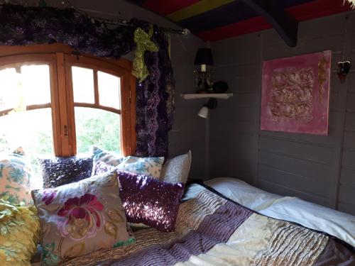 1 dormitorio con cama con almohadas y ventana en La roulotte de Glorit, en Bourg-sur-Gironde