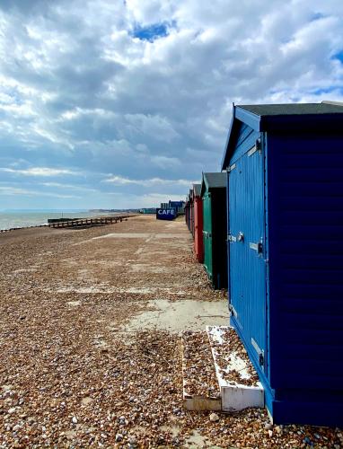 a row of colourful beach huts on the beach at 15 Grosvenor in Hastings