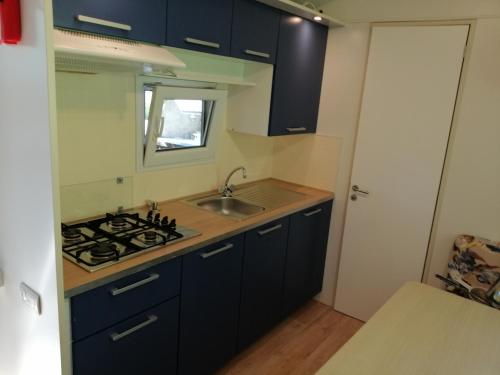 cocina con armarios azules, fregadero y fogones en Samson mobile house, en Bled