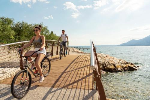 a man and a woman riding bikes on a bridge over the water at Sunset Residence in Brenzone sul Garda