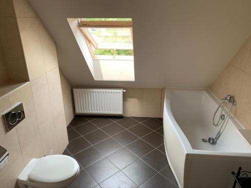 een badkamer met een toilet, een bad en een dakraam bij Robinson szigete in Balatonfüred
