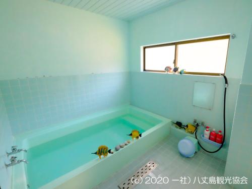 a bathroom with a tub filled with blue tiles at Kokumin Shukusha Sun Marina in Kaminato