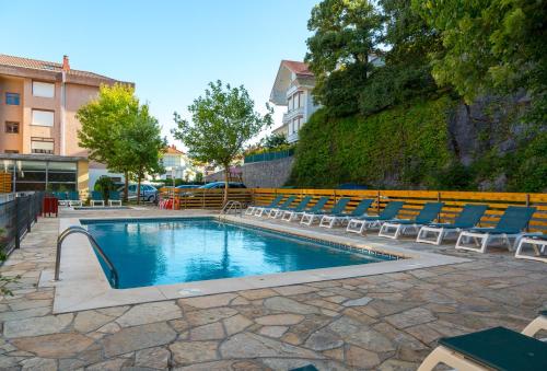 a swimming pool with lounge chairs and a swimming pool at Apartamentos Los Arces in Isla