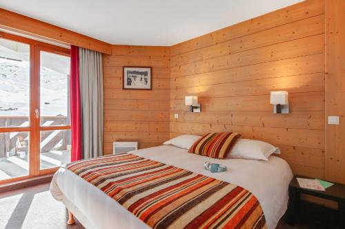 a bedroom with a bed with a wooden wall at Résidence Pierre & Vacances Le Tikal in Val Thorens