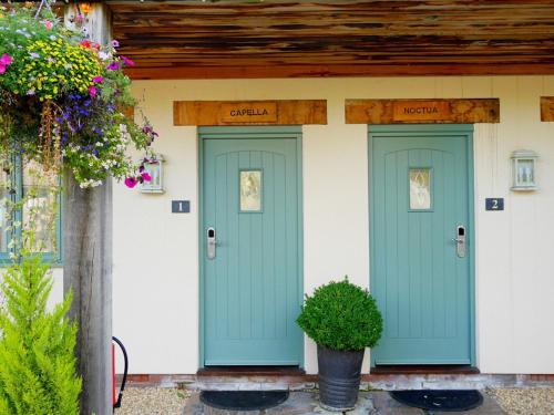 two green doors on a house with flowers at The Sun Inn in Swindon