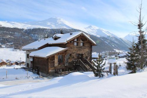 een blokhut in de sneeuw met een berg bij Chalet Mistral in Livigno