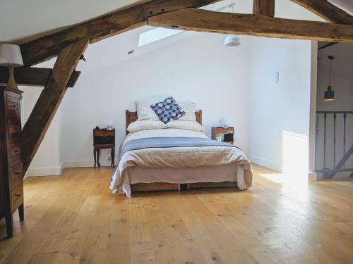 um quarto com uma cama e piso em madeira em Gîte Rue des Fleurs Puycelsi em Puycelci