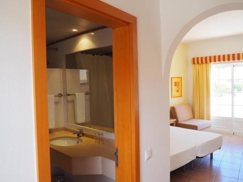 une salle de bain avec un lavabo, un lit et un miroir dans l'établissement Club House CVL, à Luz