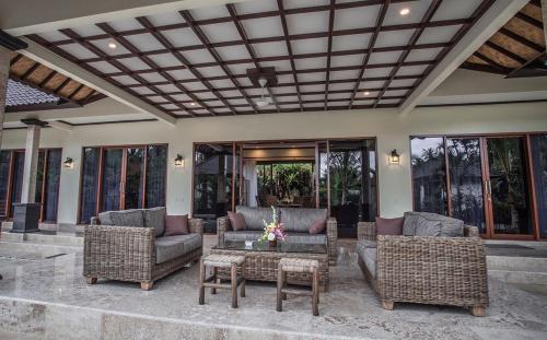 a patio with wicker chairs and a table at Villa Barong in Candidasa
