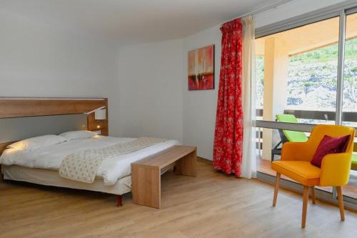 een slaapkamer met een bed, een stoel en een raam bij Hotel Grand Canyon du Verdon in Aiguines