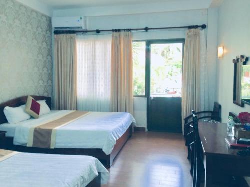 a hotel room with two beds and a window at Cong Doan Hotel Vung Tau in Vung Tau