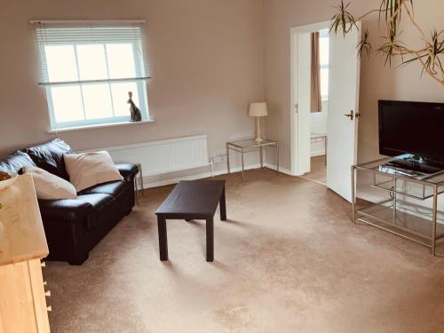 a living room with a couch and a table and a tv at The Stables Apartment in Newark upon Trent