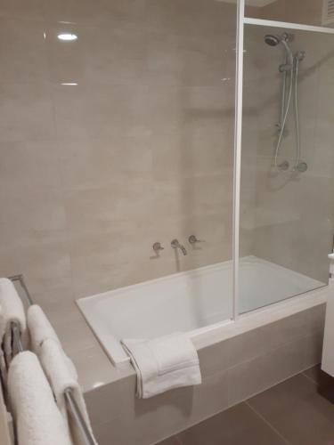 a bathroom with a shower and a bath tub with towels at Central City Exclusive Apartments in Perth