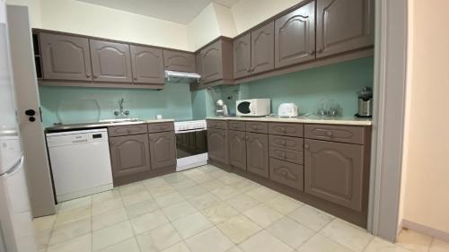 a kitchen with brown cabinets and white appliances at Lusitania T2 Frente Mar em Quarteira in Quarteira