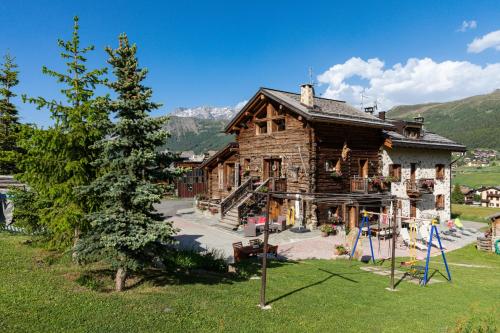 a wooden house with a playground in front of it at Chalet Mistral in Livigno
