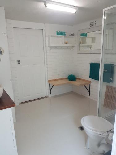 uma casa de banho branca com um WC e um chuveiro em Forest view bungalow em Nambucca Heads