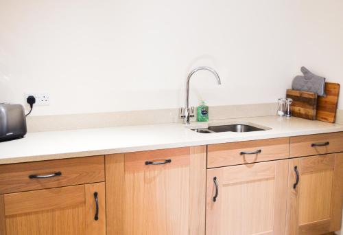 a kitchen with wooden cabinets and a sink at Bluebell Cottage at The Old Tractor Barn in Brackley