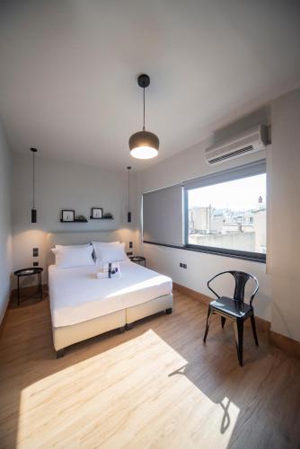 a bedroom with a bed and a chair and a window at Urban Sea View Lofts #2 in Chalkida