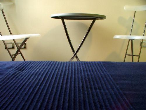 um quarto com duas cadeiras, uma mesa e uma cama em Caracciolo 10 em Nápoles