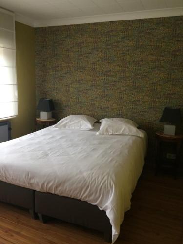 a bedroom with a large bed with white sheets and pillows at Le Lendemain in Lovendegem