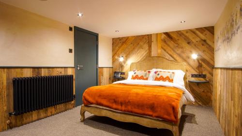 a bedroom with a bed with a wooden wall at The Farm House in West Malling