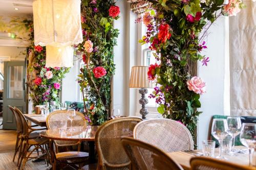 a restaurant with tables and flowers on the walls at The Farm House in West Malling