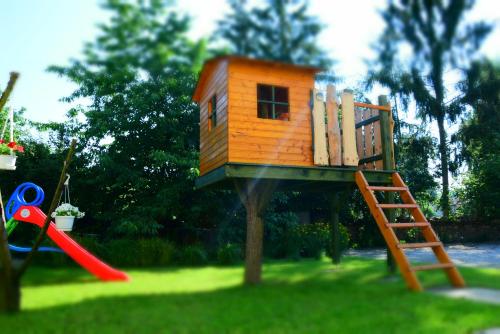 a wooden play house with a ladder and a slide at La Siesta Bogács Apartman in Bogács
