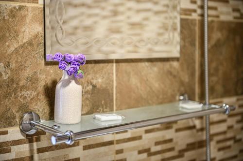 un jarrón de flores púrpuras sentado en un estante en un baño en Medi Guest House, en Sapareva Banya