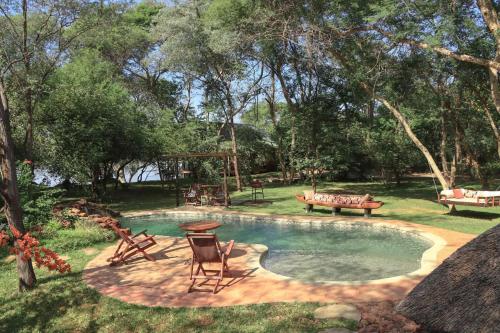 una piscina con mesa de picnic y sillas en un patio en Mama Out of Africa en Livingstone