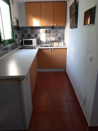 cocina con armarios de madera y suelo de baldosa en Apartamento CHINIJO en Caleta de Sebo