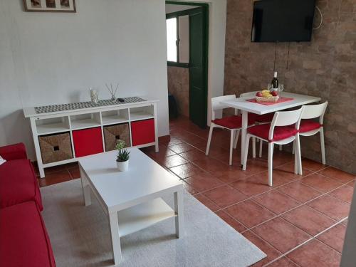 sala de estar con mesa blanca y sillas rojas en Apartamento CHINIJO, en Caleta de Sebo