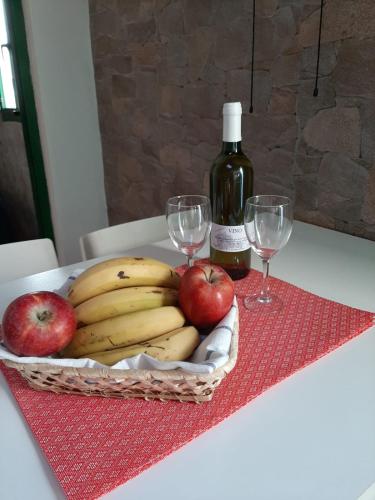 una cesta de plátanos y manzanas en una mesa con copas de vino en Apartamento CHINIJO en Caleta de Sebo