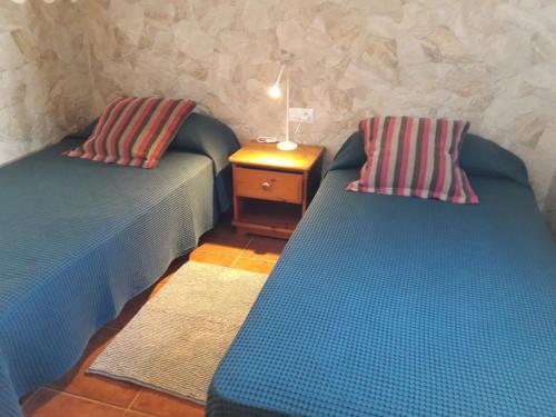two beds in a room with a night stand and a table at Apartamento CHINIJO in Caleta de Sebo