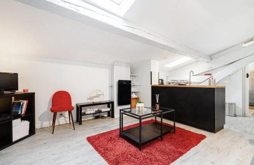 ein Wohnzimmer mit einem roten Teppich und einem Tisch in der Unterkunft Le Cocon - Chaleureux Studio Centre Ville au Calme in Toulouse