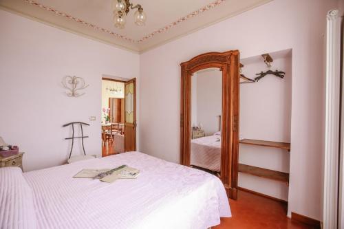 a bedroom with a white bed and a mirror at Il Pozzo Fiorito in Cossombrato