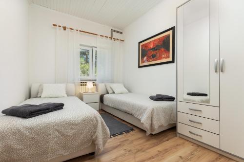 - une chambre blanche avec 2 lits et un miroir dans l'établissement Apartments Elita, à Rovinj