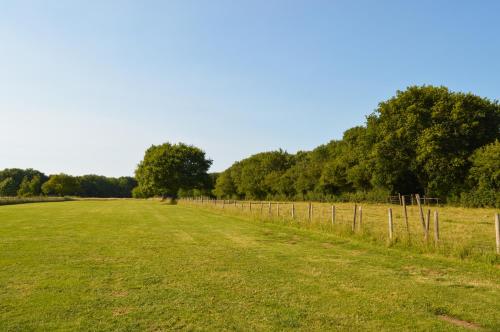 a field with a fence and trees in the background at Bluebell Cottage at The Old Tractor Barn in Brackley