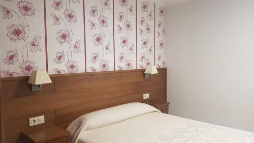 ポイオにあるCasa Fuentesのピンクの花の壁紙を用いたベッドルーム1室