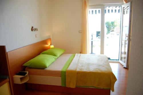 a bedroom with a bed with green pillows and a window at Studio Ante in Brela