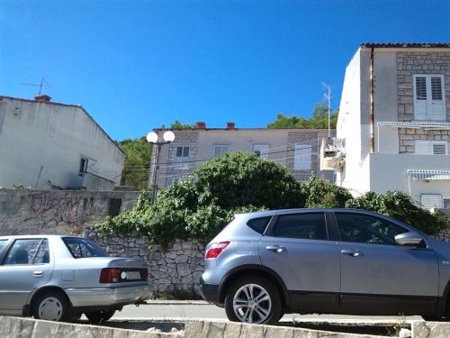 two cars parked in a parking lot in front of buildings at Rooms Katica in Korčula