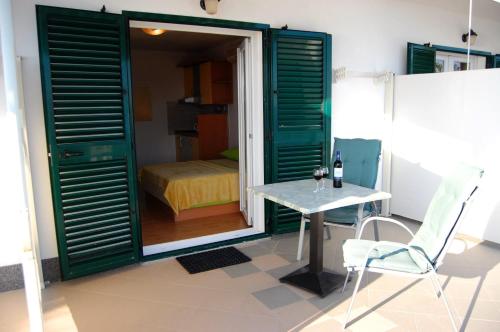 a room with green doors and a table and a bed at Studio Ante in Brela