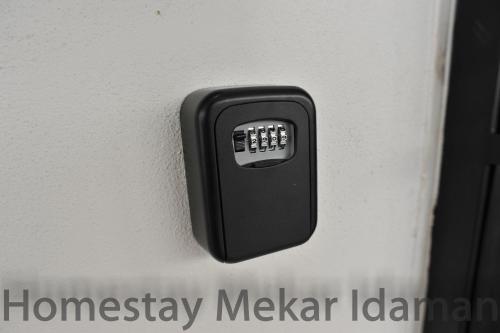 a black remote control on a white wall at homestay mekar idaman in Kepala Batas